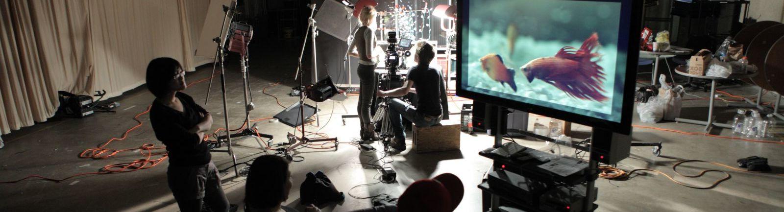 Students on a film set watch a large screen.