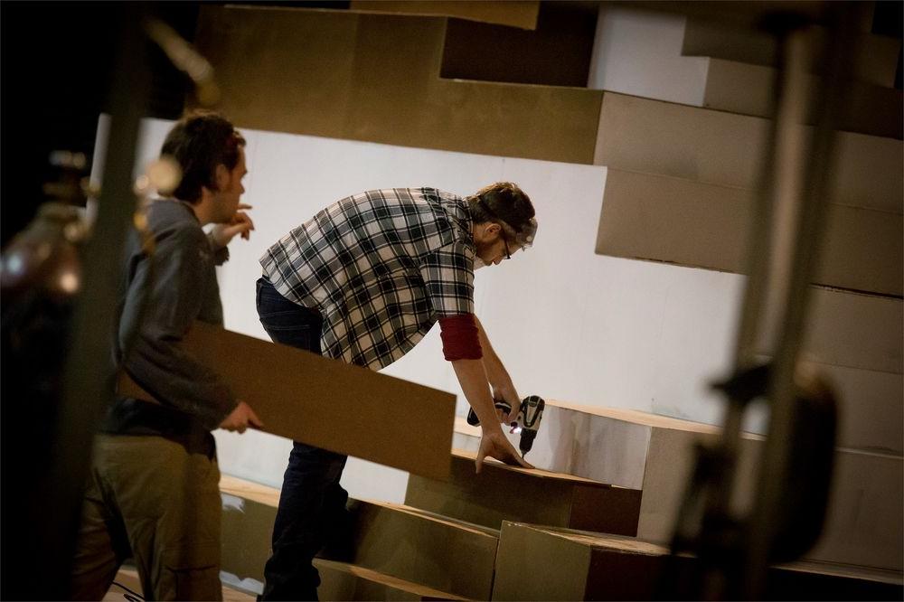 Student backstage building a prop for a theater set.